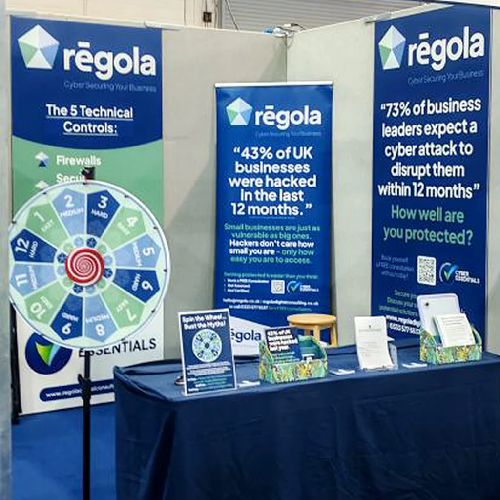Regola exhibition stand with branded banners, a cyber security spinning wheel and printed marketing materials.