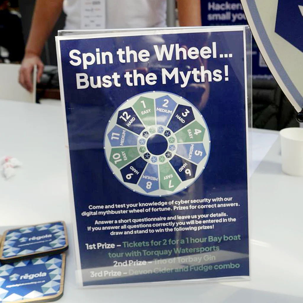 Regola tabletop display featuring the spinning wheel and the message “Spin the Wheel – Bust the Myths!”